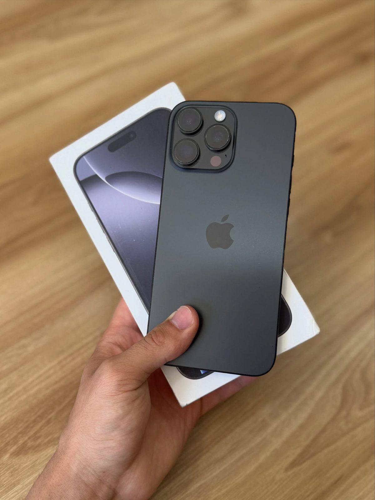 Black titanium iPhone 16 Pro Max with box in hand - Legacy Luxury Store Ghana